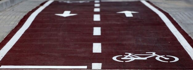 A close-up of a well-maintained bike lane separated from car traffic by a physical barrier. The bike lane is clearly marked with symbols and signs, indicating a safe route for cyclists.