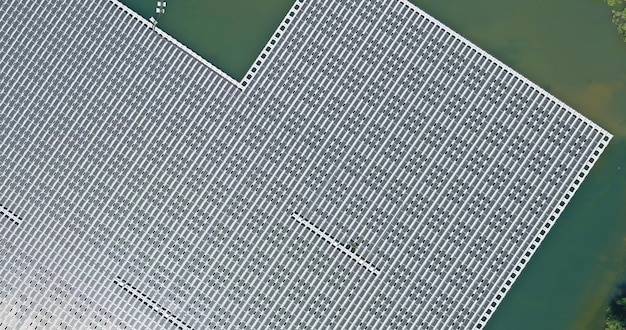 An aerial view of a large-scale battery recycling plant. Solar panels cover the roof, showcasing the facility's commitment to renewable energy. Trucks are seen delivering used EV batteries, while other areas of the plant display processed materials ready for reuse.